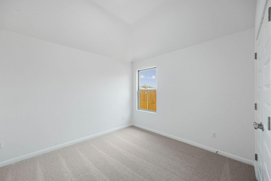 Carpeted spare room with lofted ceiling and baseboards