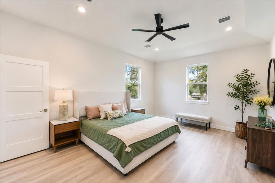 Primary Bedroom: Spacious and bright with modern finishes, wood-look flooring, and a relaxing, airy feel.