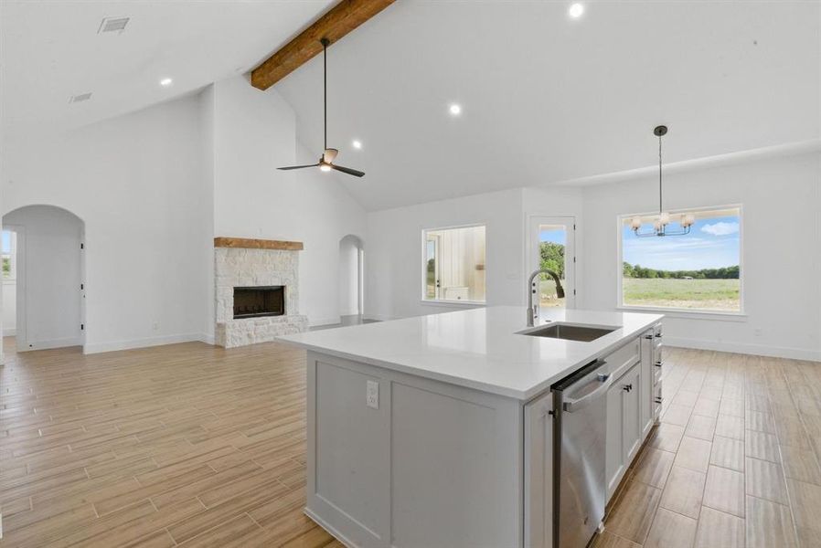 Kitchen with ceiling fan, wood tiled floors, beam ceiling, high vaulted ceiling, and a fireplace Kitchen with ceiling fan, wood tiled floors, beam ceiling, high vaulted ceiling, and a fireplace