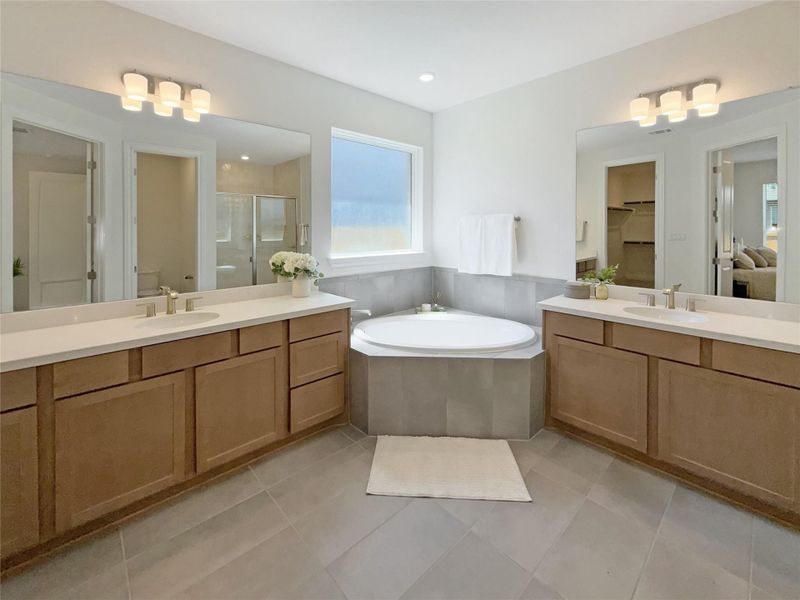 Full bathroom featuring two vanities, a bath, light tile patterned flooring, and a stall shower