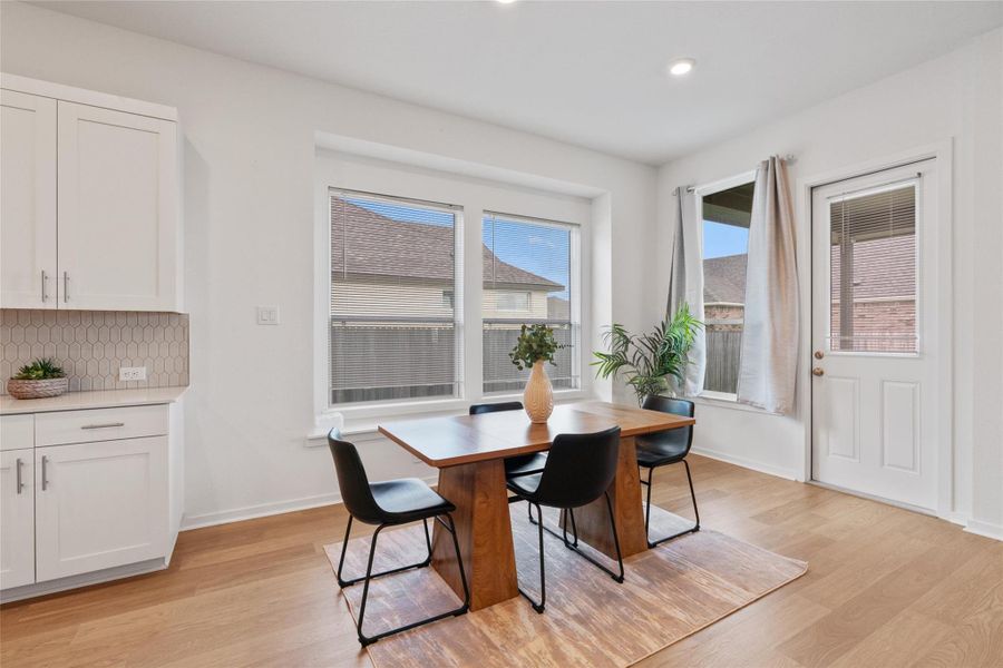 A well-lit dining space featuring durable wood type flooring and ample natural light.