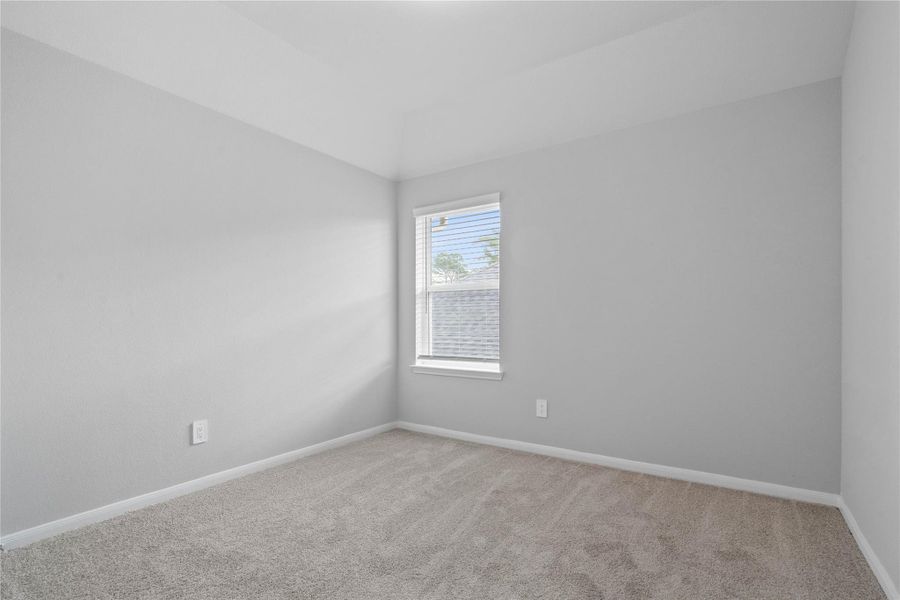 This cozy secondary bedroom offers plush soft carpeting, neutral walls ready for personalization, a sun-filled window with fitted blinds, sloped ceilings, and a spacious closet for all your storage needs.