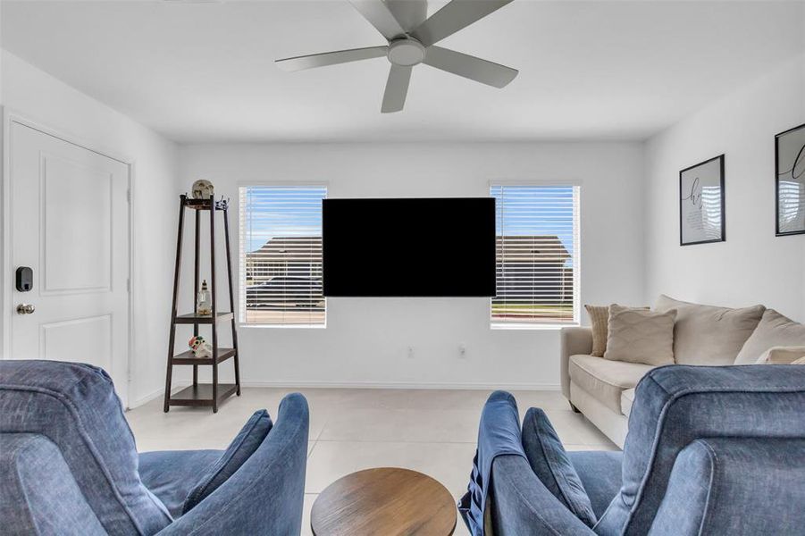 Tiled living area featuring healthy amount of natural light and a ceiling fan