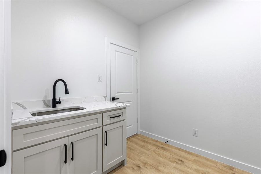 Bathroom with vanity, wood finished floors, and baseboards