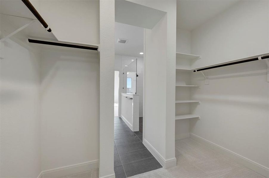 Walk in closet with light tile patterned flooring and light colored carpet Walk in closet with light tile patterned flooring and light colored carpet