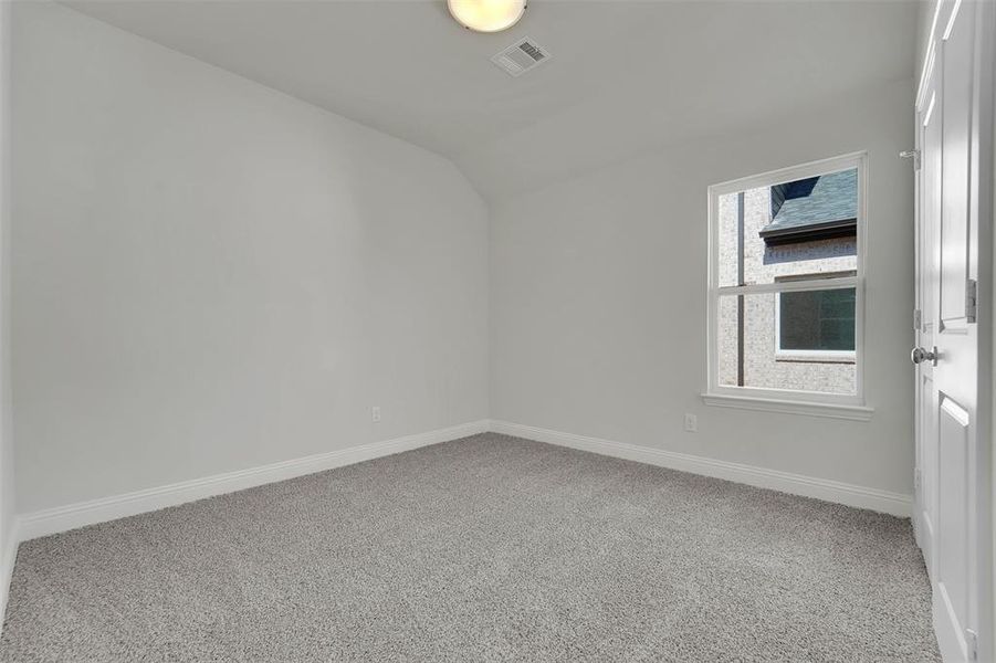 Unfurnished room featuring carpet floors, baseboards, visible vents, and lofted ceiling