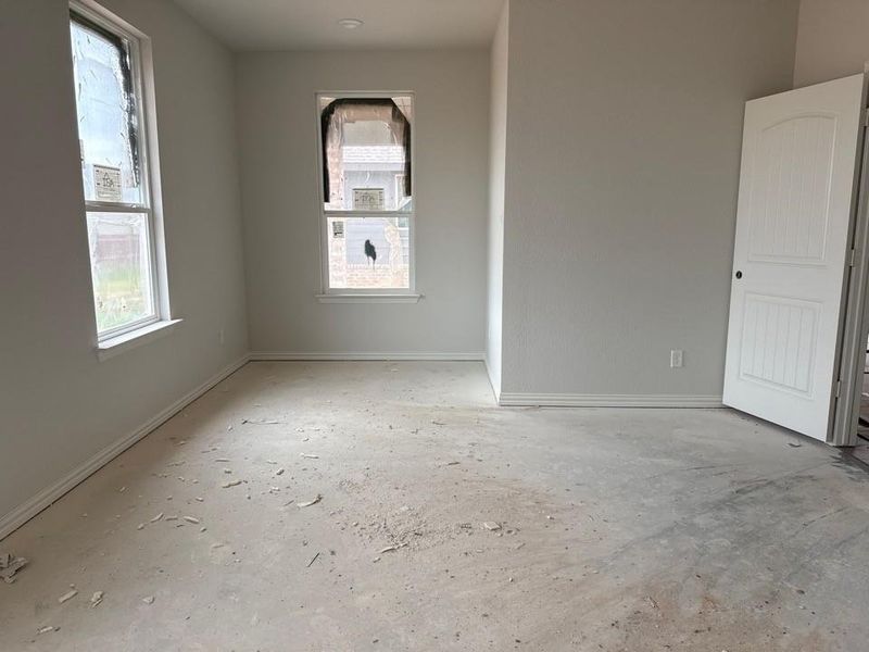 Room with two windows, a white paneled door, and a light-colored unfinished floor