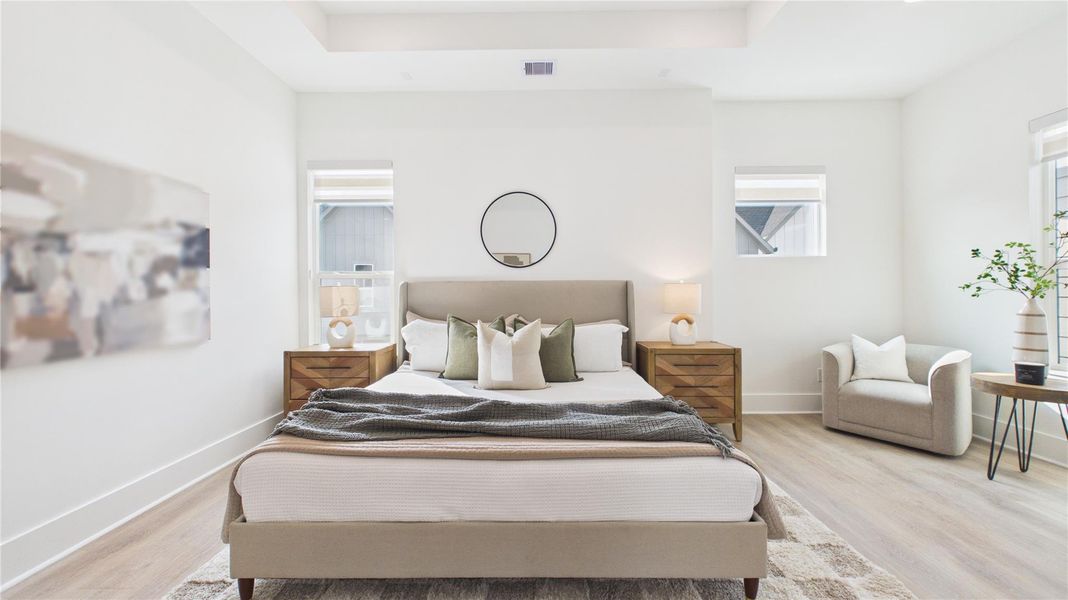 This is a bright, modern bedroom featuring a comfortable bed with neutral bedding, two wooden nightstands with lamps, and a cozy armchair. The room is accented with minimalist decor and natural light from two windows, creating an inviting atmosphere.