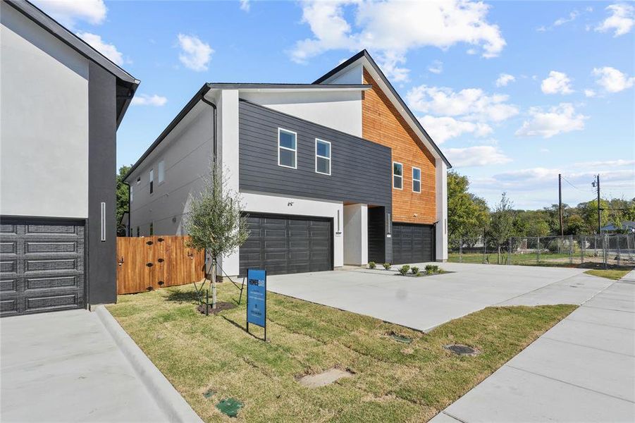 View of home's exterior with an attached garage, driveway, stucco siding, and a gate