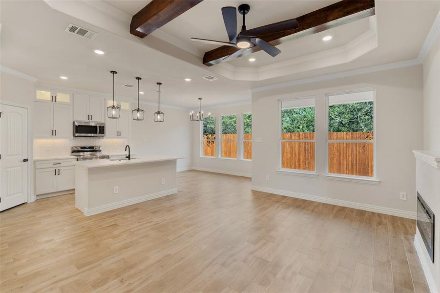 Kitchen with ceiling fan with notable chandelier, stainless steel appliances, white cabinetry, and light hardwood / wood-style flooring