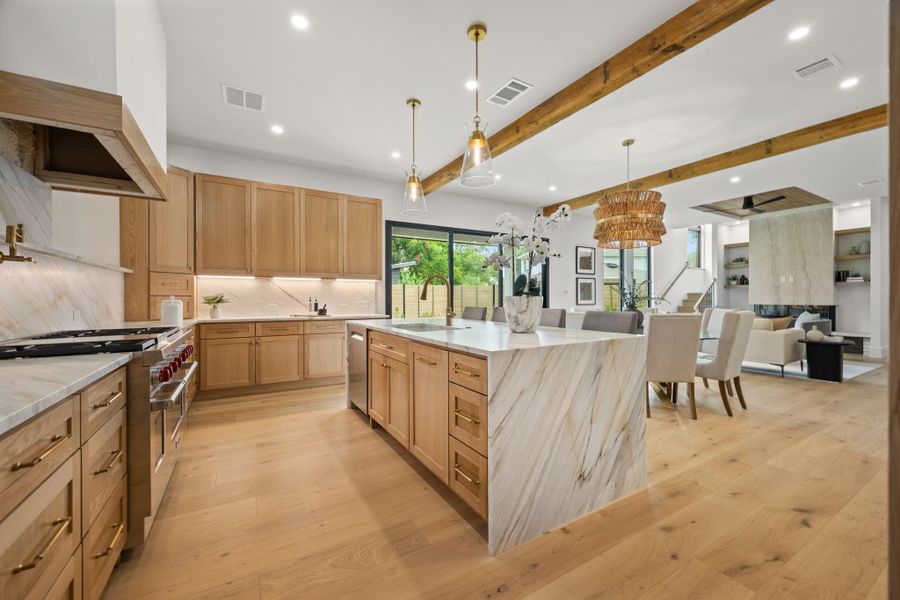 Natural wood tones complement the marble surfaces in this open architectural kitchen.