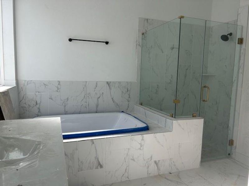 Primary bathroom with seamless glass shower and gold fixtures Primary bathroom with seamless glass shower and gold fixtures