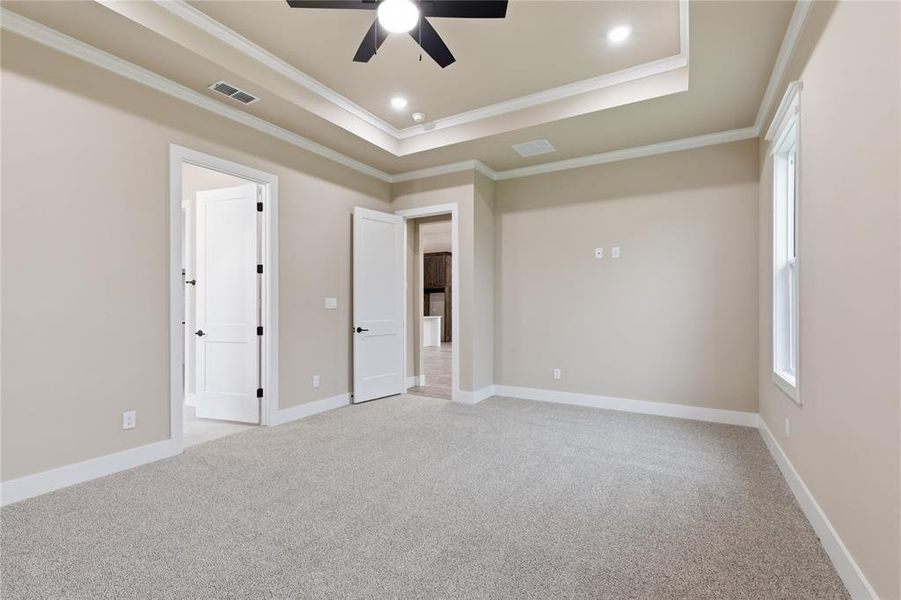 Spacious room featuring tray ceiling with recessed lighting and a ceiling fan, light-colored carpeting, and neutral wall paint Spacious room featuring tray ceiling with recessed lighting and a ceiling fan, light-colored carpeting, and neutral wall paint