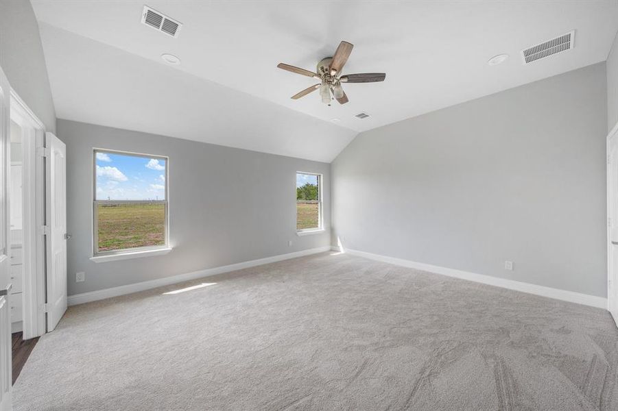 Empty room with lofted ceiling, carpet, and ceiling fan