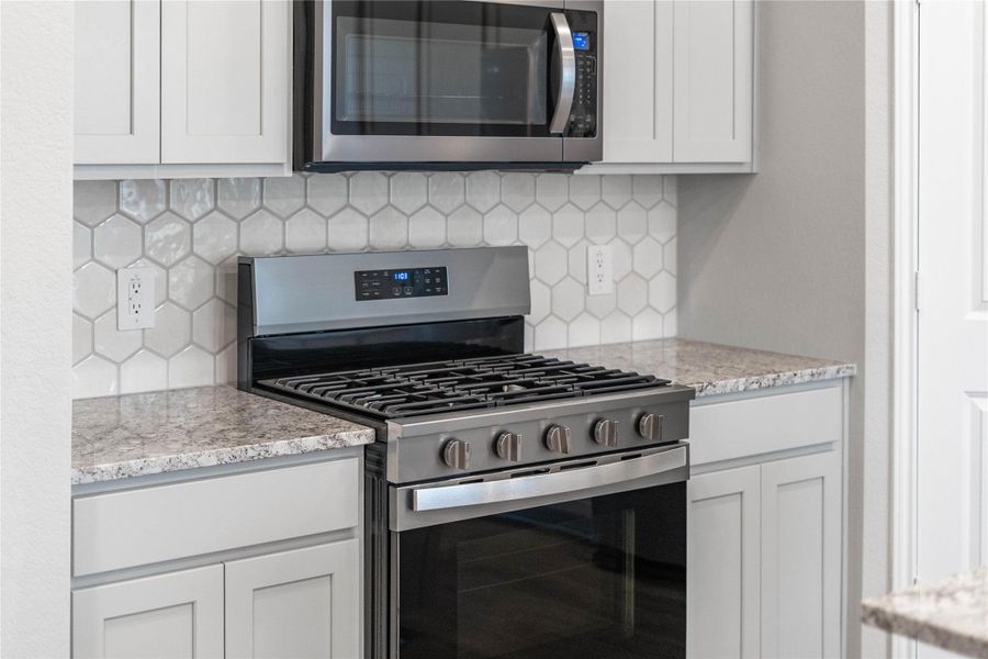 Showcased here is a Whirlpool gas range, paired with a steam microwave equipped with sensor cooking—all framed by an elegant tile backsplash.