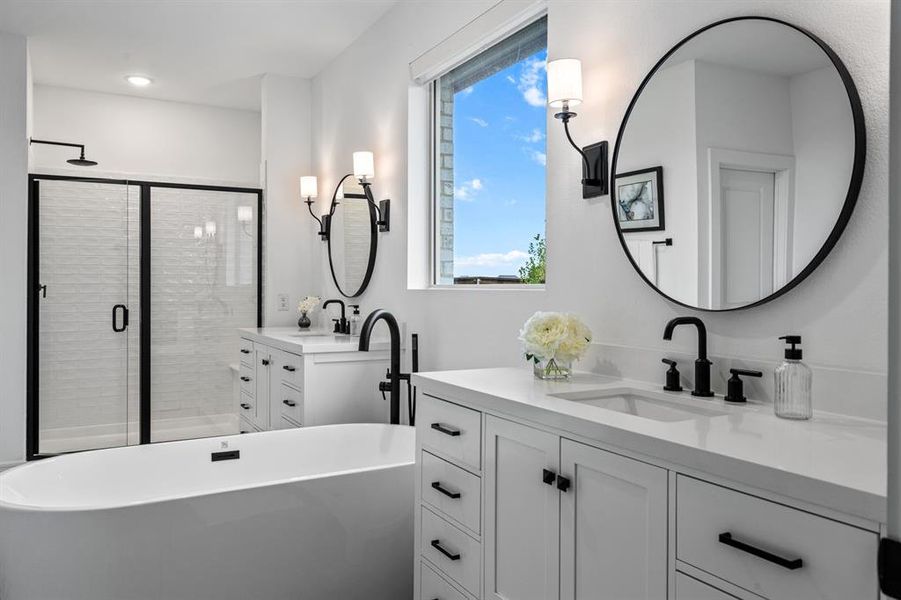Primary bathroom with two vanities, a soaking tub, and a stall shower
