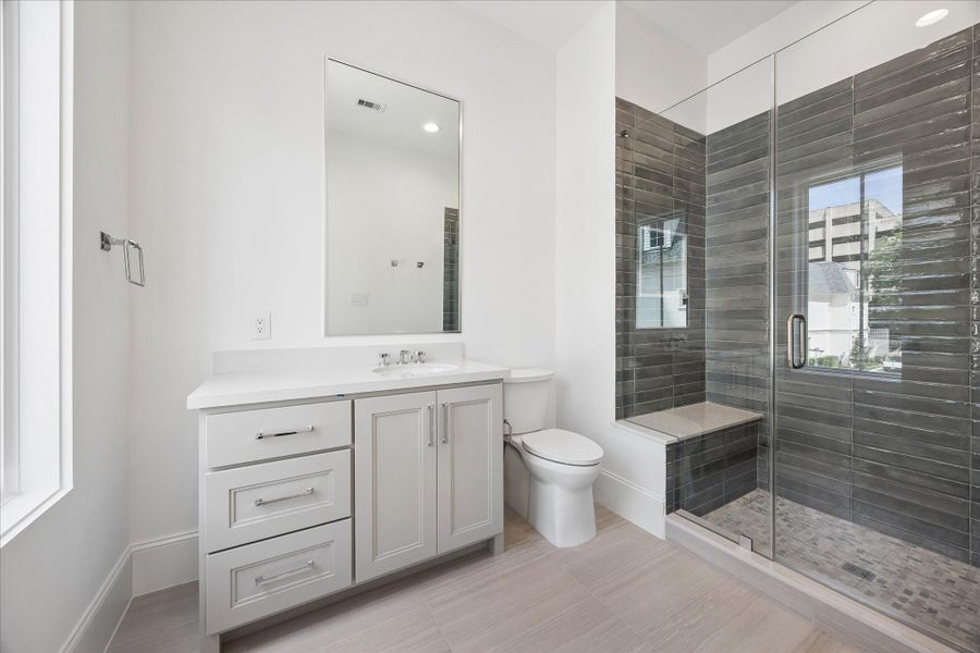 En-suite bathroom features a sleek, glass-encased shower, Quartz counters and additional counter and storage space.