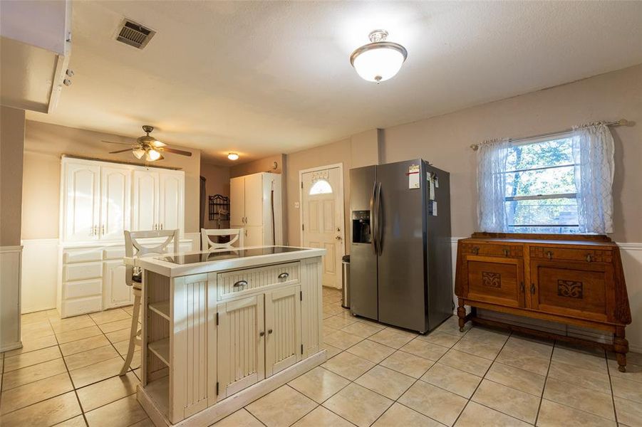 Kitchen featuring stainless steel fridge, light tile patterned floors, a kitchen island, and healthy amount of natural light Kitchen featuring stainless steel fridge, light tile patterned floors, a kitchen island, and healthy amount of natural light