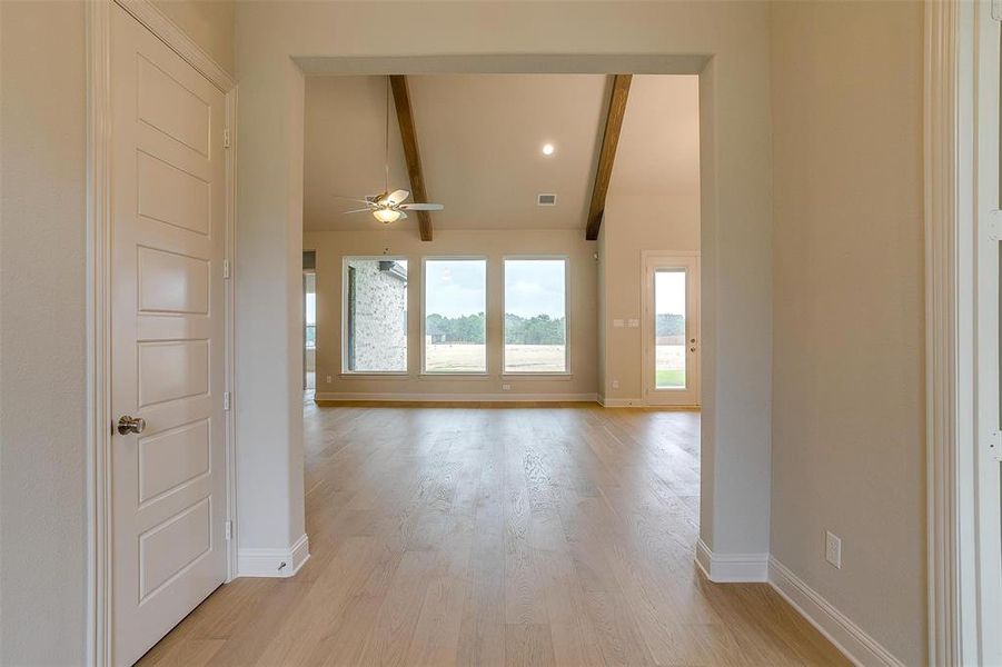 Hallway with light hardwood / wood-style flooring and lofted ceiling with beams