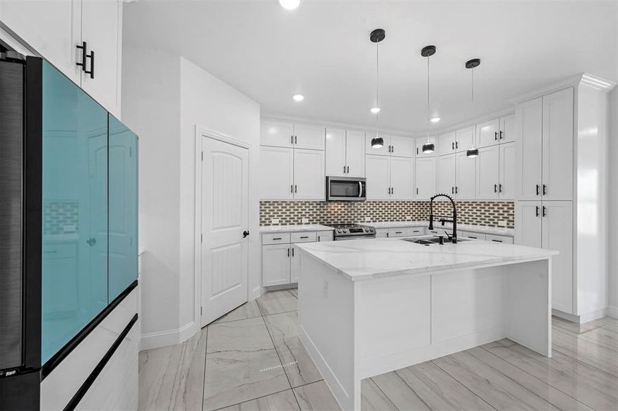 Kitchen featuring backsplash, sink, appliances with stainless steel finishes, and white cabinetry