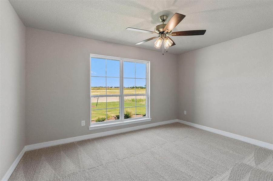Neutral-toned interior featuring a ceiling fan with integrated lighting, a large window, light gray carpeting, white baseboards, and painted walls Neutral-toned interior featuring a ceiling fan with integrated lighting, a large window, light gray carpeting, white baseboards, and painted walls