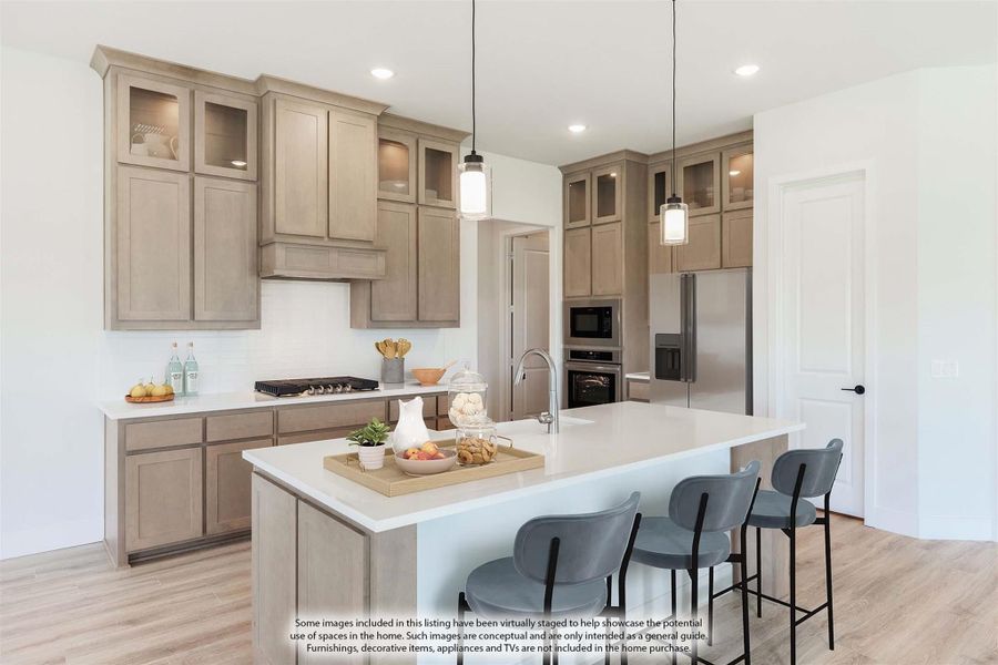Kitchen with tan wood cabinets, large island with seating, pendant lights, and stainless steel appliances