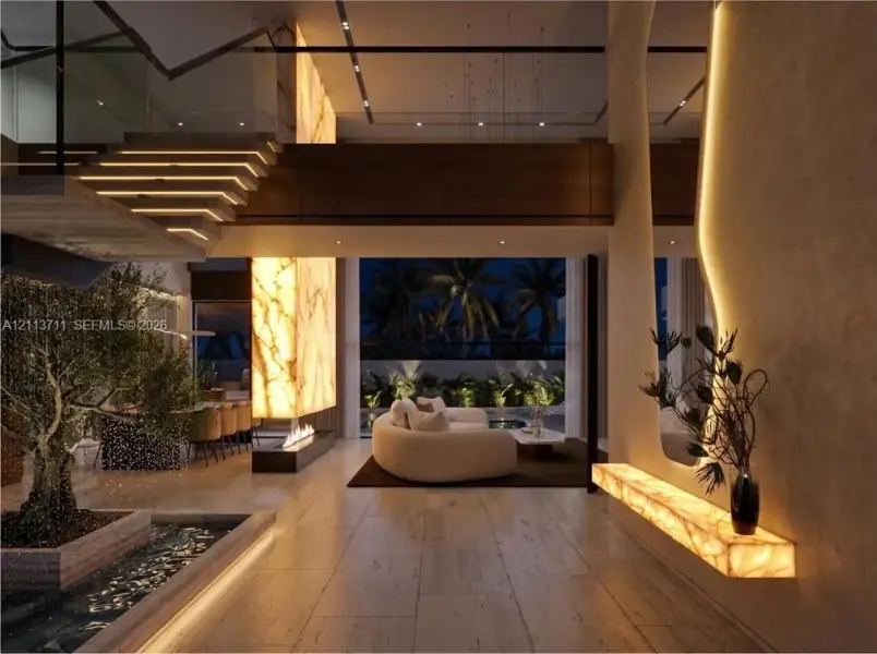 Open-concept living space featuring wood-finish flooring, a full-height backlit stone accent wall, a floating staircase with integrated lighting, and an indoor reflecting pool