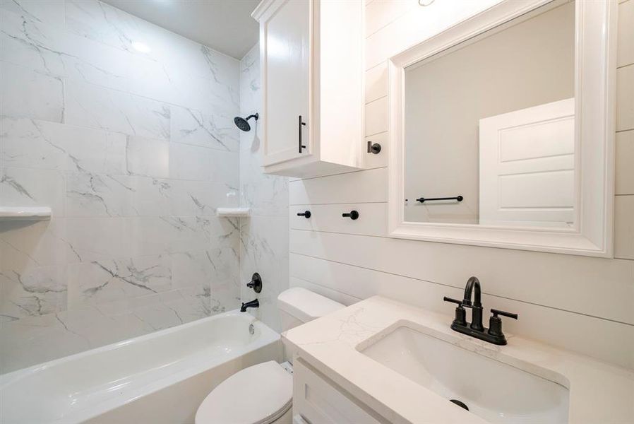 Full bathroom featuring tiled shower / bath, vanity, and toilet