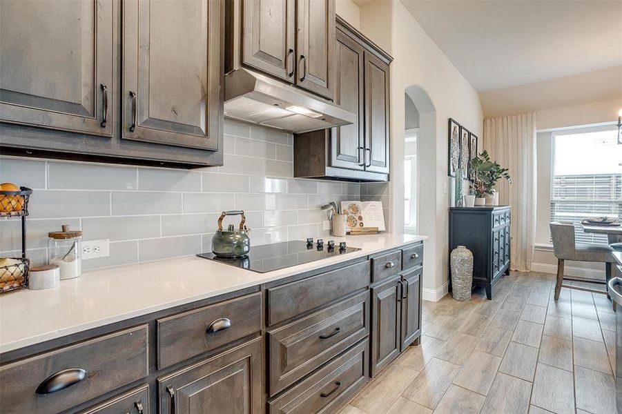 Kitchen featuring dark brown cabinets, backsplash, black electric cooktop, and light hardwood / wood-style floors