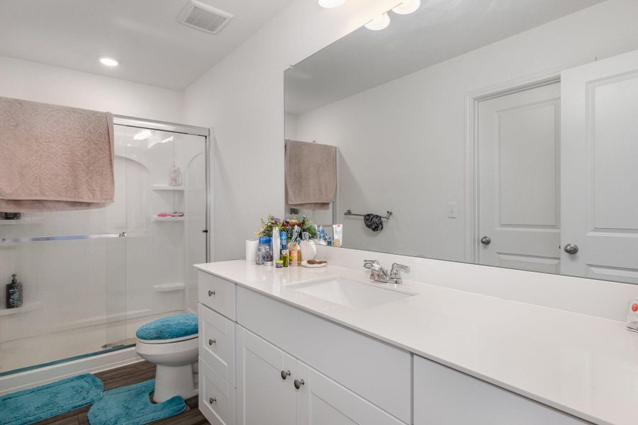 Bathroom with hardwood / wood-style flooring, toilet, a shower with door, and vanity