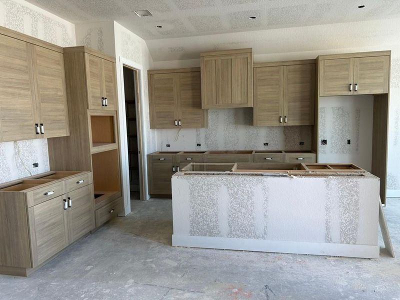 Kitchen featuring a center island, lofted ceiling, and unfinished concrete floors Kitchen featuring a center island, lofted ceiling, and unfinished concrete floors