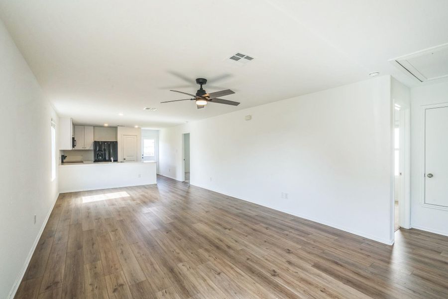 Natural light illuminates the open-concept living area, showcasing rich hardwood flooring and a functional ceiling fan. Natural light illuminates the open-concept living area, showcasing rich hardwood flooring and a functional ceiling fan.