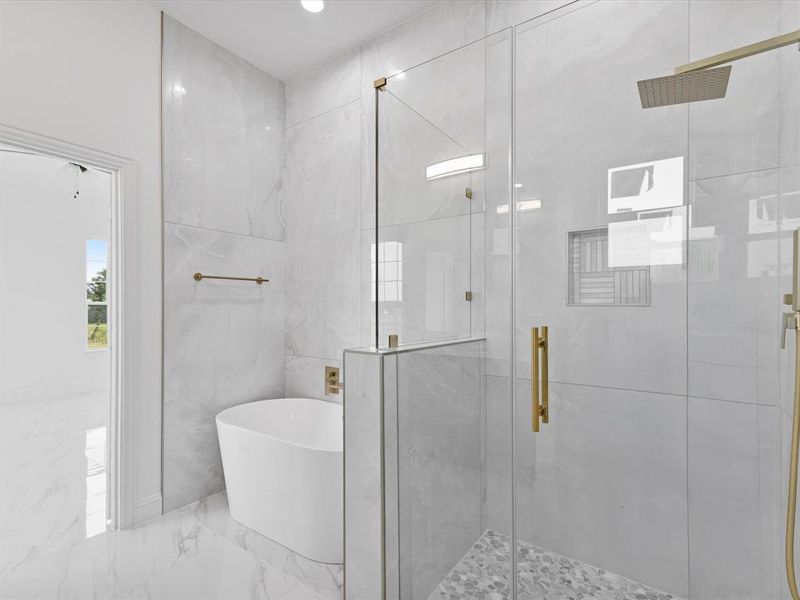 Full bath with marble tiled floors, a freestanding bath, and a stall shower