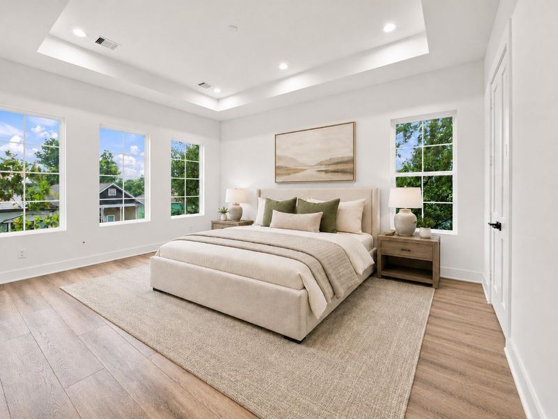 Primary bedroom has tray ceilings and an abundance of natural light.