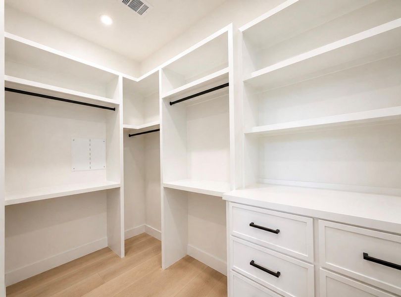 Primary walk-in closet featuring custom built-in shelving, efficient organizational design, and abundant storage space. Primary walk-in closet featuring custom built-in shelving, efficient organizational design, and abundant storage space.
