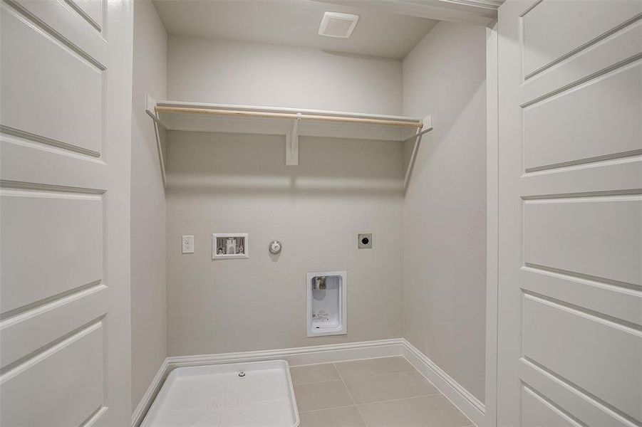 Washroom with gas dryer hookup, hookup for an electric dryer, tile patterned floors, and hookup for a washing machine Washroom with gas dryer hookup, hookup for an electric dryer, tile patterned floors, and hookup for a washing machine