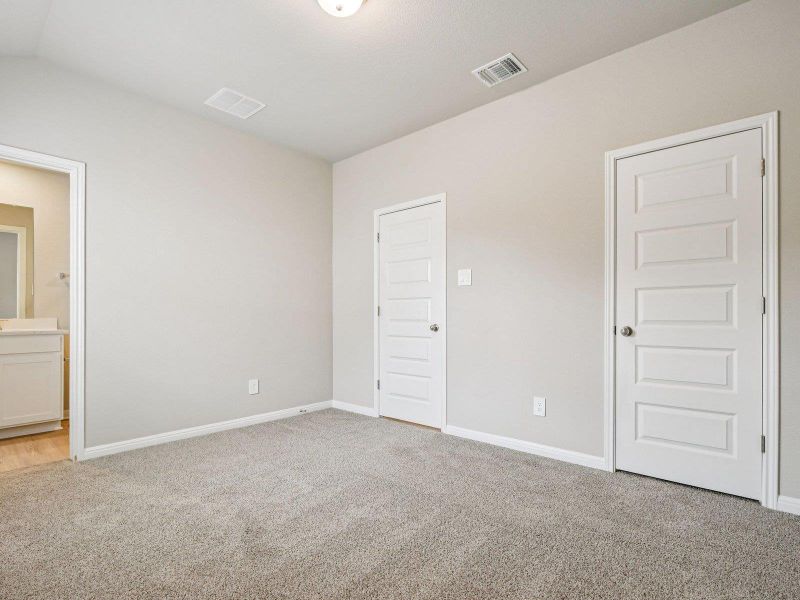 Unfurnished bedroom with light colored carpet and connected bathroom Unfurnished bedroom with light colored carpet and connected bathroom