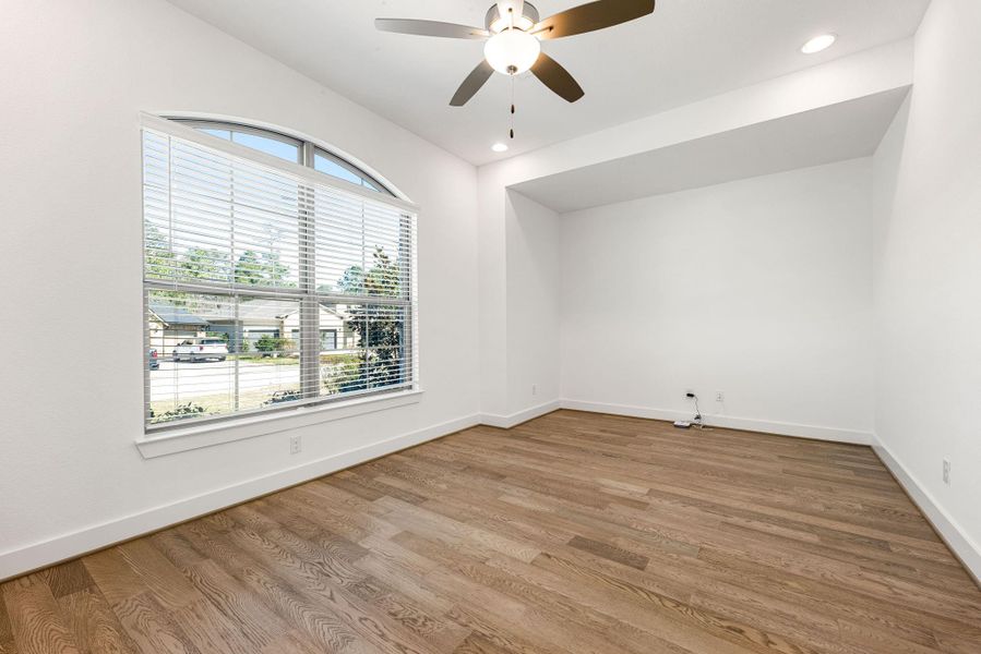 Nestled in front of the home is a dedicated home office with engineered wood flooring, dark stained ceiling fan, recessed lighting and windows and blinds. This could also be a great flex space for a game room, playroom or for anything that you may need.