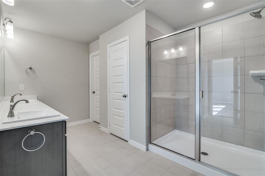 Full bathroom with a stall shower, double vanity, and light tile patterned floors Full bathroom with a stall shower, double vanity, and light tile patterned floors