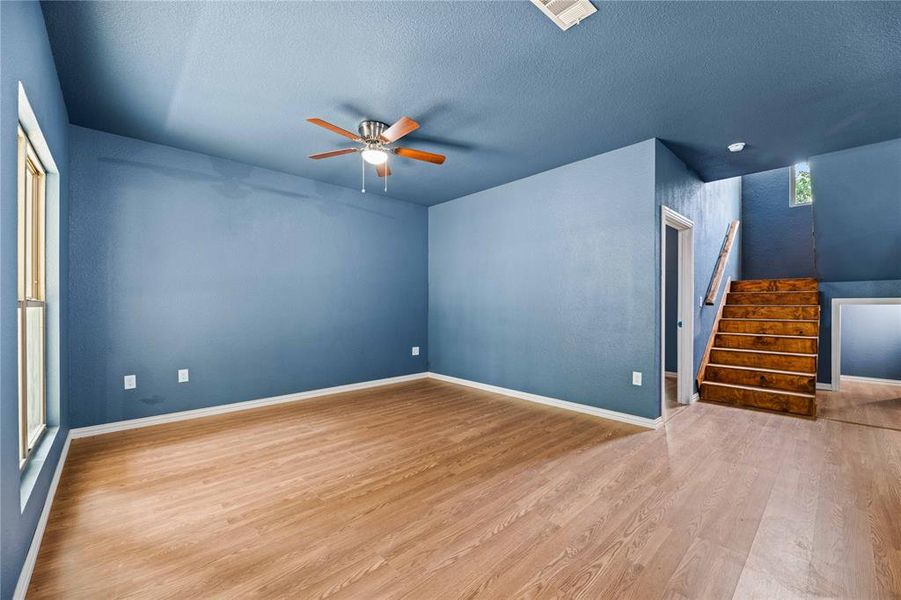 Unfurnished living room with wood-type flooring, ceiling fan, and a textured ceiling Unfurnished living room with wood-type flooring, ceiling fan, and a textured ceiling