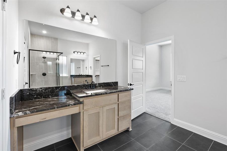 Bathroom featuring a shower stall, vanity, dark tile patterned flooring, and dark colored carpet