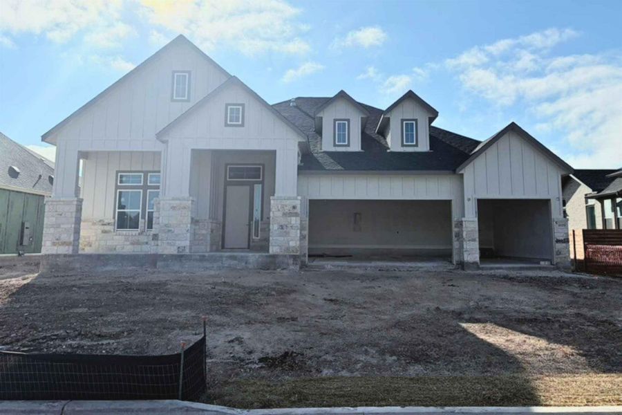 Modern inspired farmhouse featuring board and batten siding, stone siding, covered porch, and an attached garage