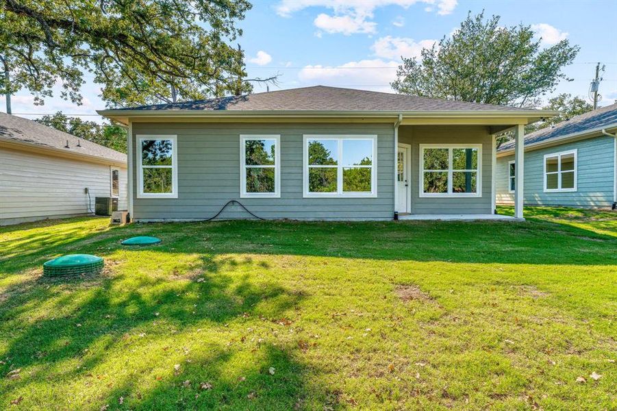 Rear view of property with a patio area, a lawn, and a shingled roof Rear view of property with a patio area, a lawn, and a shingled roof