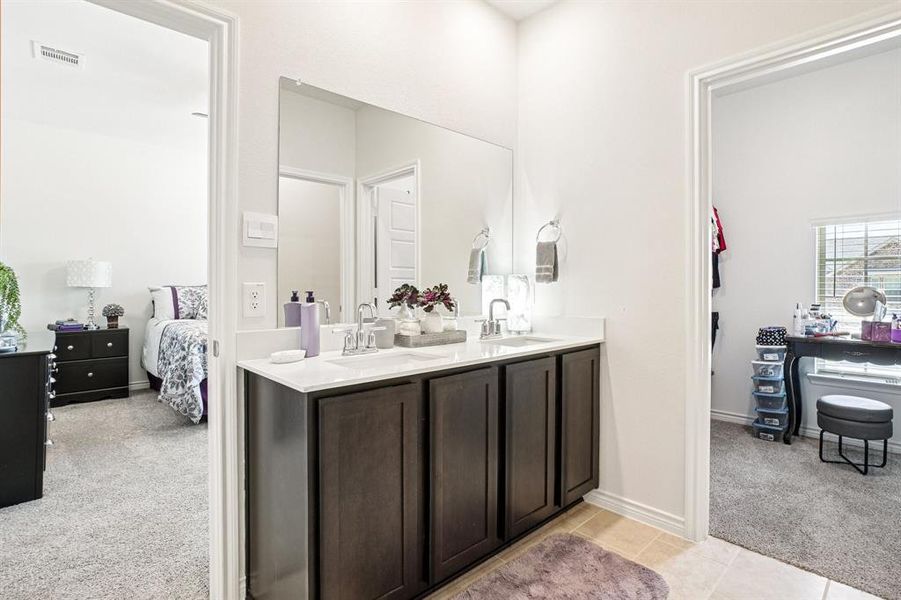 Ensuite bathroom featuring double vanity and light tile patterned floors Ensuite bathroom featuring double vanity and light tile patterned floors