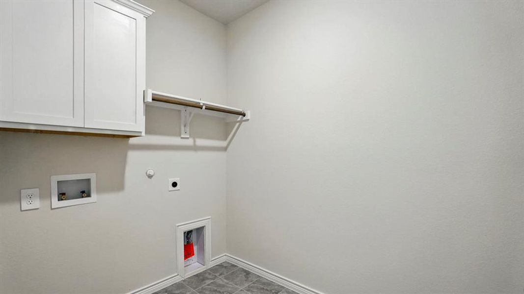 Dedicated laundry area featuring white shaker-style cabinetry with crown molding, a built-in hanging rod, and durable tile flooring Dedicated laundry area featuring white shaker-style cabinetry with crown molding, a built-in hanging rod, and durable tile flooring
