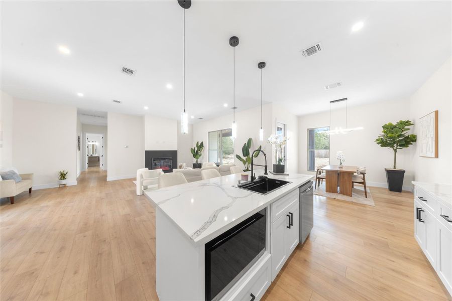 Kitchen featuring white cabinetry, open floor plan, black microwave, hanging light fixtures, and recessed lighting Kitchen featuring white cabinetry, open floor plan, black microwave, hanging light fixtures, and recessed lighting