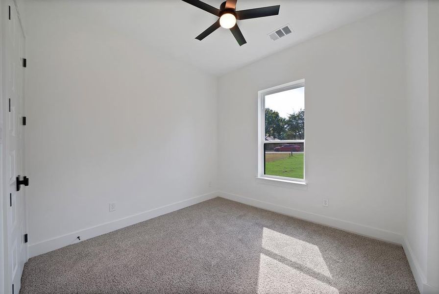 Carpeted empty room with baseboards and ceiling fan Carpeted empty room with baseboards and ceiling fan