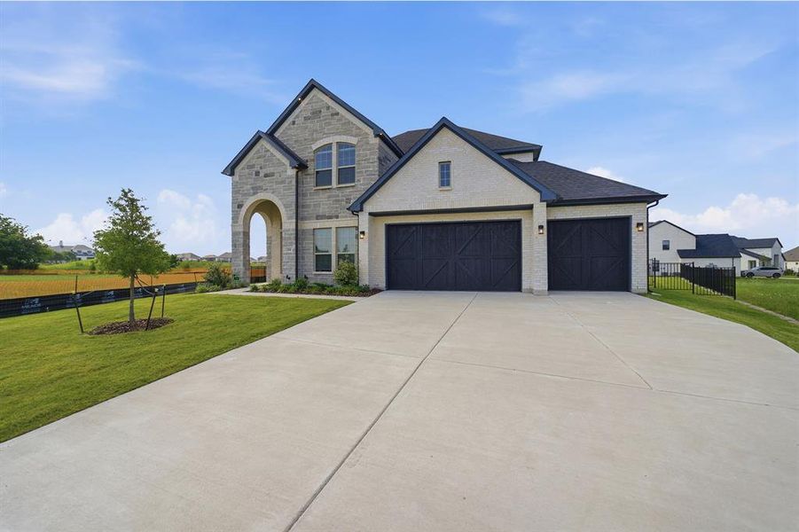 Stone and stucco exterior with dark trim and a prominent arched entryway
