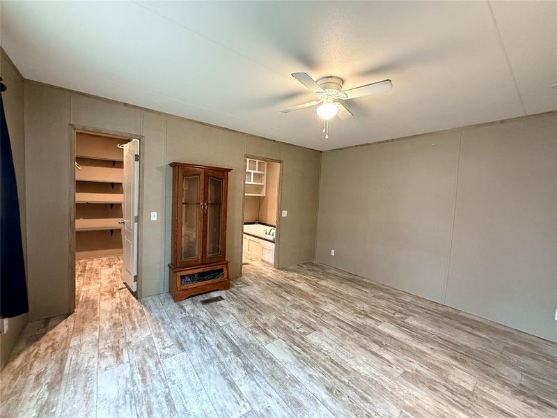 Unfurnished living room featuring light wood finished floors, a ceiling fan, and a decorative wall
