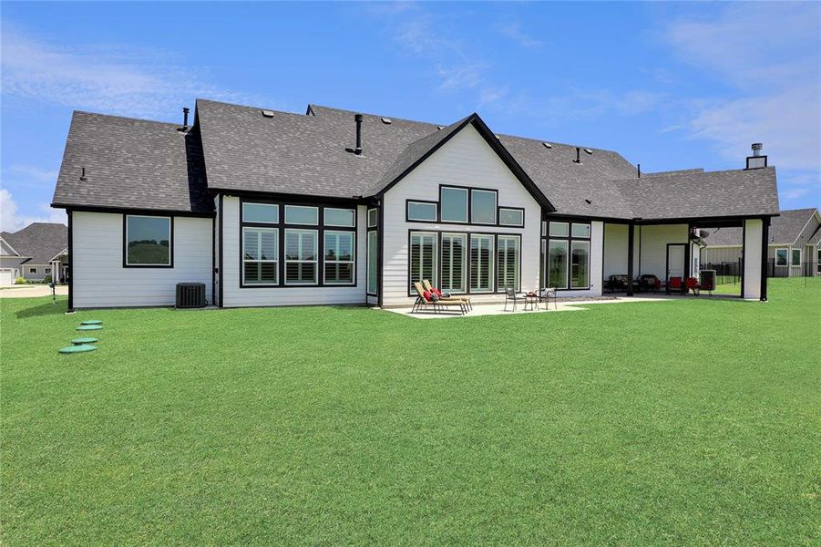 Rear view of house featuring a patio, a shingled roof, a lawn, cooling unit, and a chimney Rear view of house featuring a patio, a shingled roof, a lawn, cooling unit, and a chimney